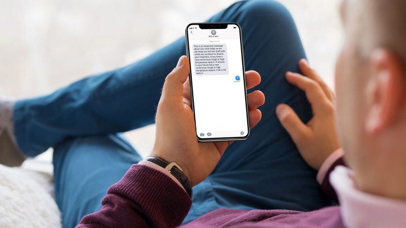 Man using phone reading SMS about appointment screen for COVID-19