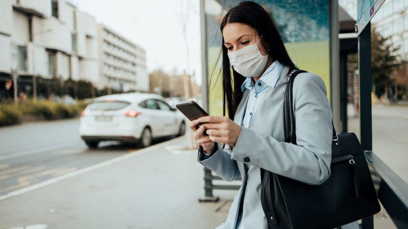 Lady at bus stop recieving SMS notifications