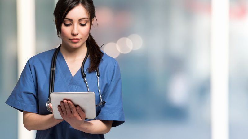 Young lady inputting data into tablet with blurred background