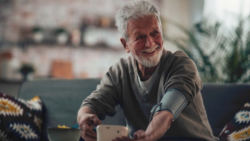 Trendy senior man with beard taking his own blood pressure