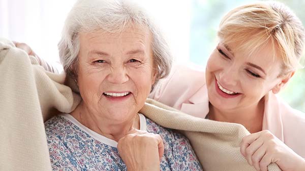 Happy older lady being cared for by younger lady at home